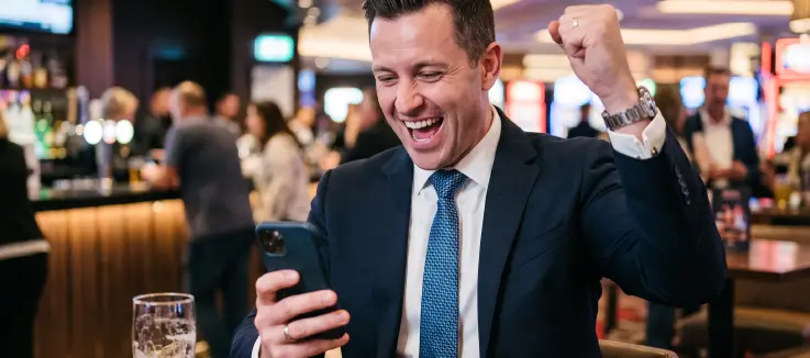 Man in a suit happy over a win on an online casino game on his phone