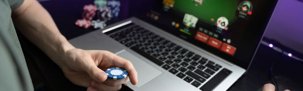 laptop screen displaying a card game with a player holding a chip looking at the screen