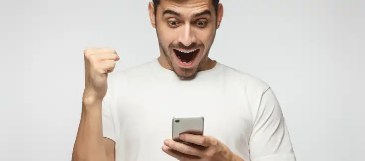 man celebrating a win on his mobile online SlotoCash casino