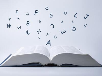 Dictionary with letters flying out of the pages